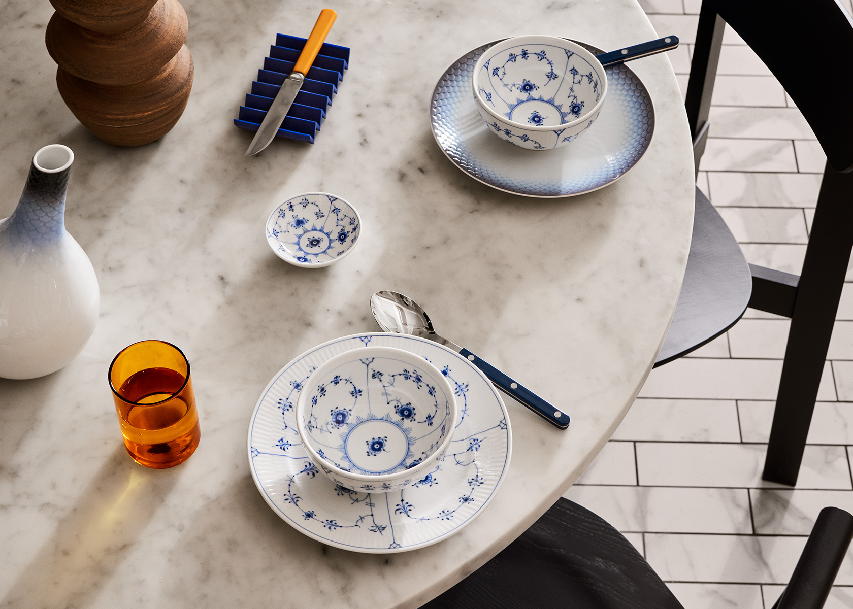 A stone table set with Blue Fluted Plain and HAV plates with two Blue Fluted Plain Bowls on top